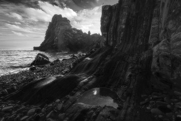 Rocky beach on the Devon coast. Black and white seascape featuring rock formation.