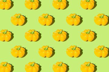 Creative pattern made of yellow bell pepper on green pastel background with shadows. Minimal style. Healthy food ingredient concept