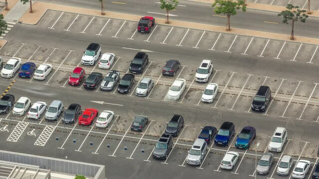 Big parking lot near mall crowded by many cars timelapse aerial view. Vehicles moves in and out