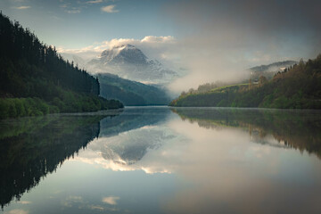 Amanecer junto a un lago con el reflejo de las montañas nevadas