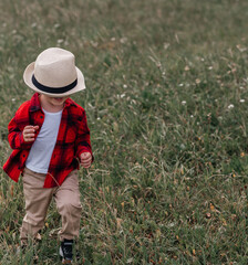 a litte boy in a red shirt playing with his hat near the mountains , summer sunset , having fun, running 