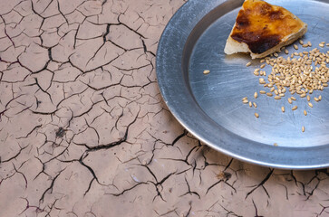 a small piece of bread and cereal grains left on the zinc plate. global famine and drought. drought disaster.
