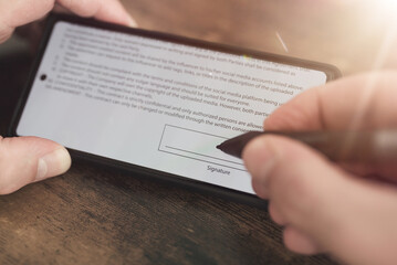 close-up view of electronic signature with stylus on smartphone screen against wooden table...