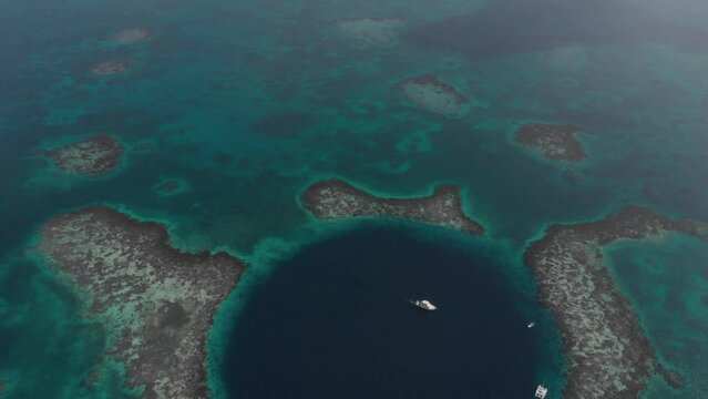 Epic Aerial view of small boats inside Great Blue Hole marine sinkhole Belize..