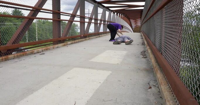 A woman rushes to help a man who fainted on a foot bridge over a busy highway