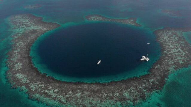 Aerial view luxury yachts inside Great Blue Hole giant marine sinkhole Belize..