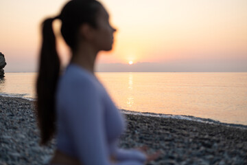 Young woman practice yoga and meditation near the sea at sunrise, healthy lifestyle concept, lotus position close-up on hands