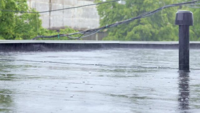 Raindrops knock on the roof, heavy rain, downpour. The flat roof of the building is covered with a waterproof material that protects from rain. Ruberoid, rolled roofing and waterproofing material.