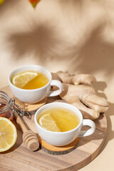 Obraz na płótnie Canvas Cup of hot tea with ginger, honey and lemon on the beige background vertical photo