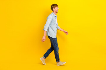 Photo of pretty positive man wear jeans shirt walking looking empty space isolated yellow color background
