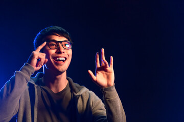 active attractive asian handsome male adult wearing smart glasses hand finer pressing turn function on glasses while smiling confident cheerful face expression studio shot dark background