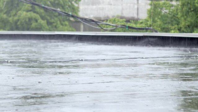 Raindrops knock on the roof, heavy rain, downpour. The flat roof of the building is covered with a waterproof material that protects from rain. Ruberoid, rolled roofing and waterproofing material.