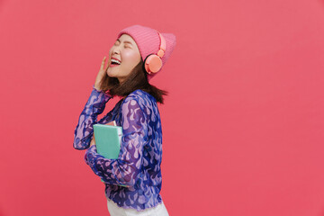 Young beautiful happy asian girl in headphones holding books