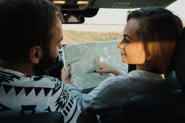 Middle aged couple on a road trip, caucasian man and woman planning next stop on the map while sitting inside car