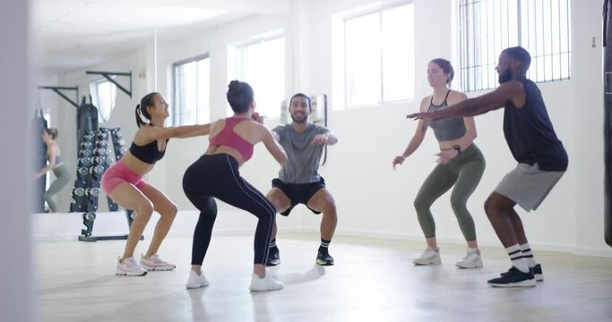 Health, squat exercise and fitness class with an instructor or personal trainer training healthy, active and athletic clients in the gym. Group of fit people doing aerobic workout in a sports club
