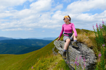 Naklejka na ściany i meble A young woman is enjoying the beauty of the Ukrainian Carpathians against the background of a mountain landscape