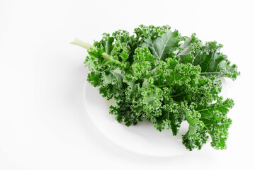 Green kale cabbage leaves on white background. Textured leaves in white plate. Top view and copyspace. Healthy food concept.