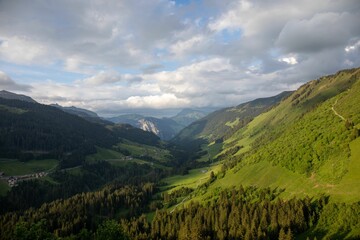 Aerial view of the green slopes of the valley under the cloudy sky
