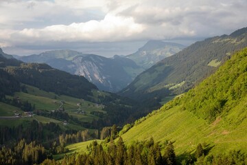 Aerial view of the green slopes of the valley under the cloudy sky