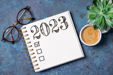 New year resolutions 2023 on desk. 2023 resolutions list with notebook, coffee cup on table. Goals,...