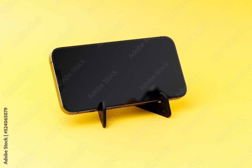 Poster smartphone with a tiny stand isolated on a yellow background
