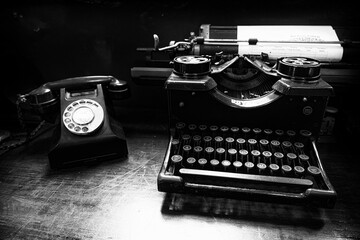 Old retro phone near retro typewriter in black and white