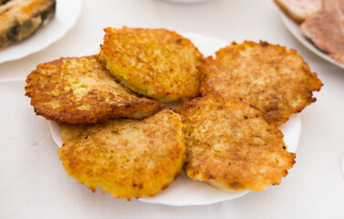 Fried grated potato pancakes with sour cream on white plate