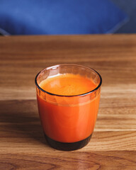 Glass of freshly squeezed carrot juice on wooden table
