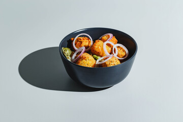 Salad with deep-fried cheese balls and red onions. Hard light, deep shadow