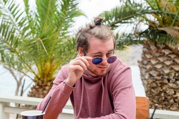 Handsome caucasian boy with a man bun winking to the camera through his sunglasses