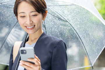 女性・雨・傘・スマートフォン