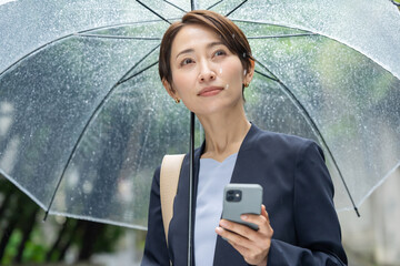 女性・雨・傘・スマートフォン