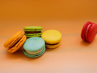 Close-up of French dessert for coffee. Multicolored macarons or macaroons on orange background. High quality photo