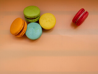 Close-up of French dessert for coffee. Multicolored macarons or macaroons on orange background. High quality photo