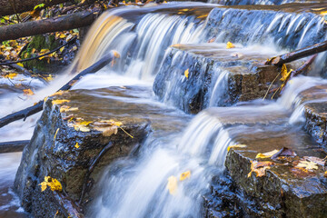Fototapeta na wymiar Falling water in a creek with autumn colored leaves