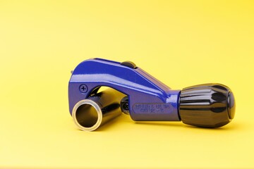 Blue Pipe cutter with an aluminum pipe isolated on yellow background