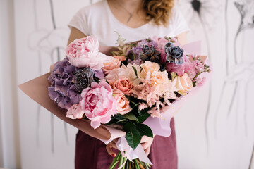 Very nice young woman holding big and beautiful bouquet of fresh roses, carnations, peony, matthiola in tender pink and purple colors, cropped photo, bouquet close up - 524072600