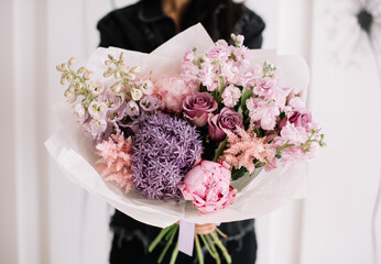 Very nice young woman holding big and beautiful bouquet of fresh delphinium, hydrangea, peony, matthiola in pastel pink and purple colors, cropped photo, bouquet close up - 524072624