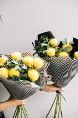 Very nice young woman holding two cute and beautiful bouquets of fresh yellow cornflowers on the grey wall background, cropped photo, bouquet close up - 524072634