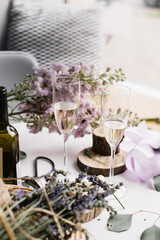 Two glasses of white wine, wine bottle, with delphinium flowers on the white table on the background