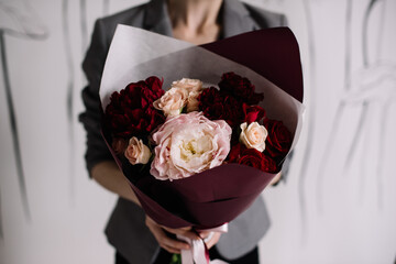 Very nice young woman holding big and beautiful wedding bouquet of fresh roses and peony flowers in pink and burgundy colors, cropped photo, bouquet close up