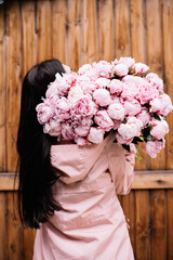 Very nice young woman holding big and beautiful mono bouquet of fresh tender pink peonies, cropped...