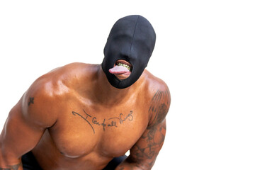 Shirtless tattooed African American man with eyeless black mask, gold fangs, and tongue sticking out