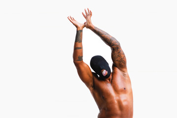 Shirtless tattooed African American man with eyeless black mask, gold fangs, and hands above head