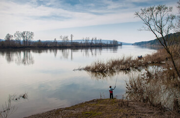 fishing on the river bank in the morning. spring fishing in nature. lonely fisherman with a fishing rod on the shore.