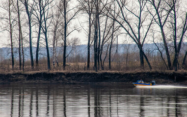fishing on the river bank in the morning. spring fishing in nature. motor boat with a fisherman floats on the river