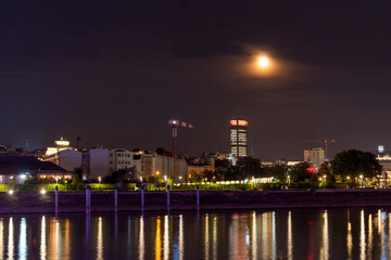Fototapeta na wymiar Belgrade and river Sava at night. Beautiful city view with moon over the city
