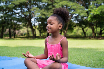 Portrait African American kid girl training yoga meditate in the park	