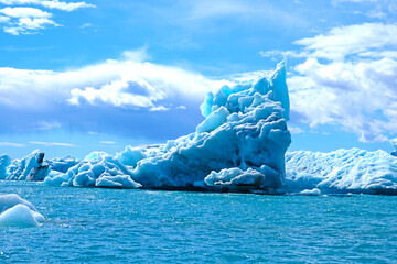 A huge piece of translucent blue and turquoise ice is a beautiful iceberg that broke away from  glacier in the ocean off the coast of Iceland
