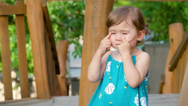 Sad toddler girl rubbing her eyes, weak eyesight problems